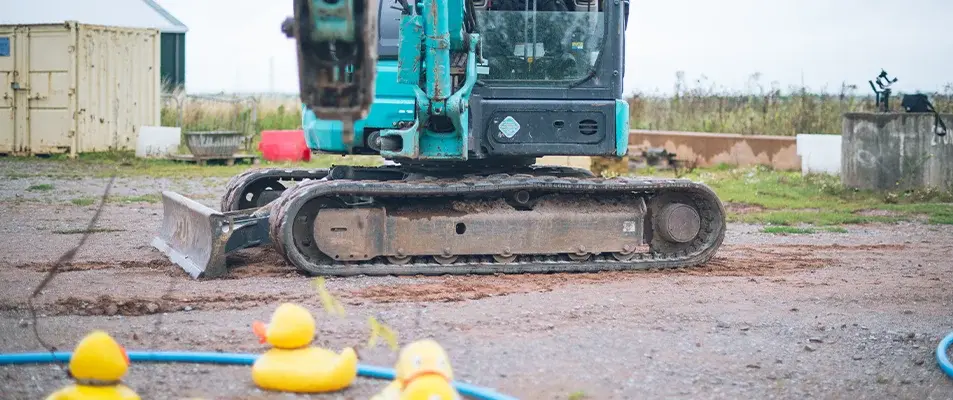 Apprentice in a digger taking part in a hook a duck task