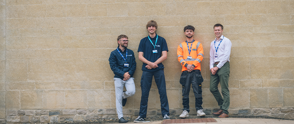 Group of apprenticeships outside leaning against a wall and smiling