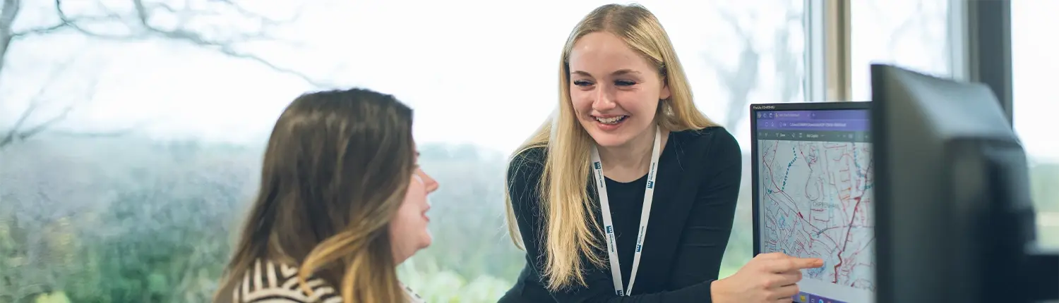 Wessex Searches Employees looking at searches on a computer and talking and smiling