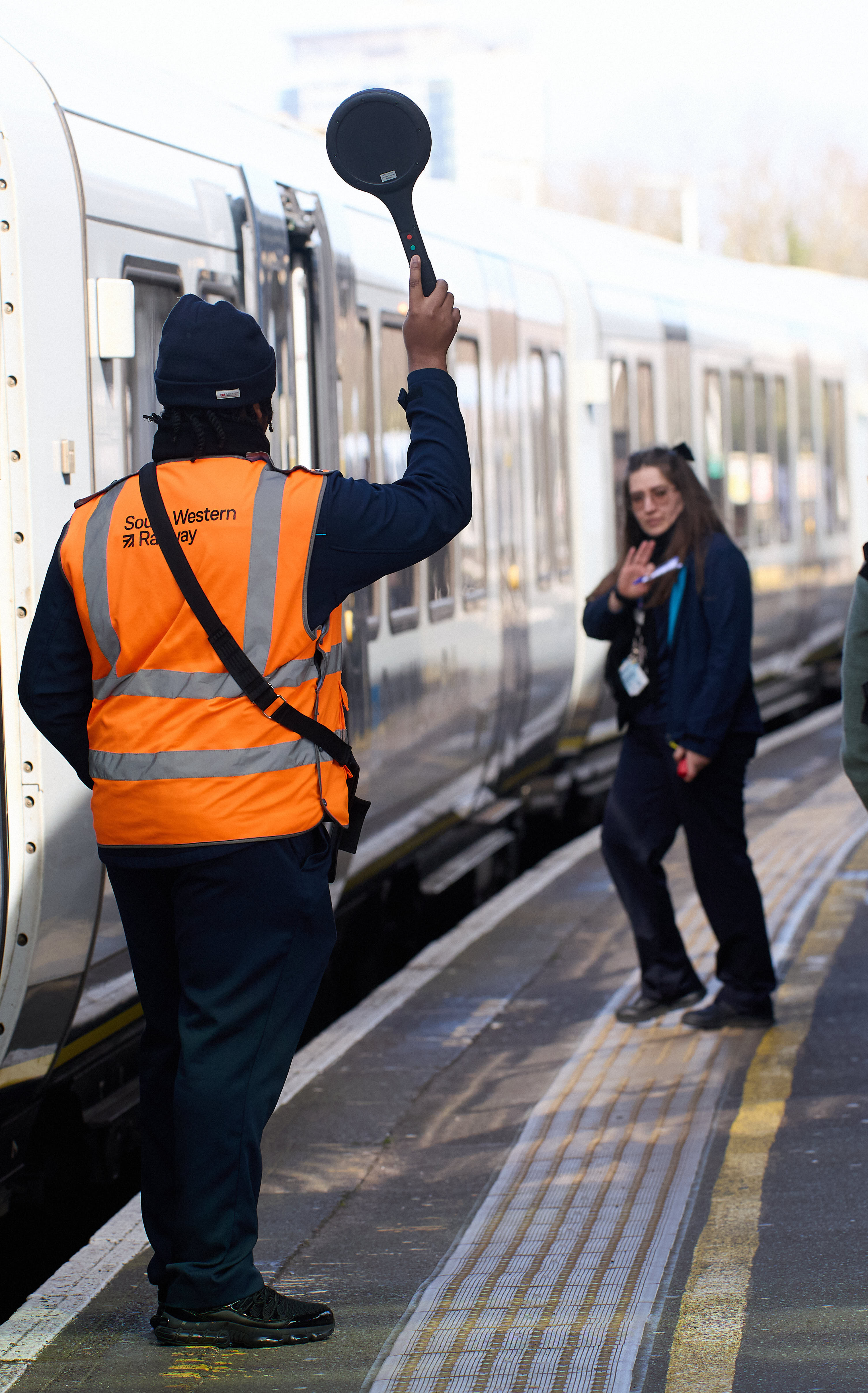 South Western Railway guard and Rail Operator 2 standing on a station platform beside a train.