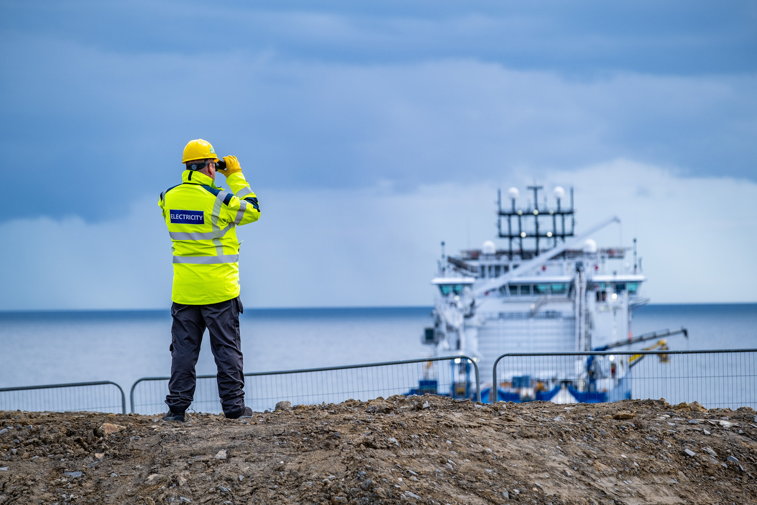 male SSE employee looking at an SSE asset through binoculars