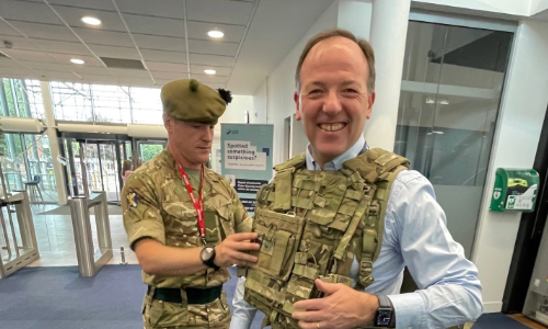John Stewart, HR Director at SSE trying on army camoflage gear with someone helping him put it on