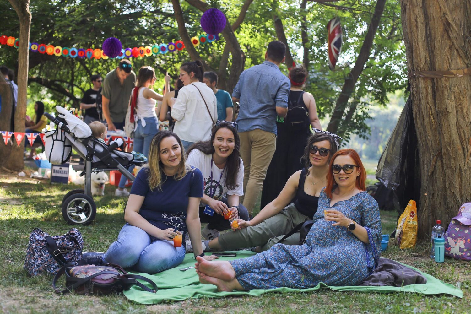 A group of people at a picnic smiling at the camera while sitting on grass.