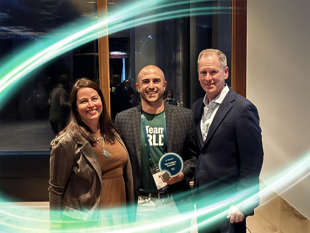 Three people are standing side by side. One has a trophy in their hand and is wearing a forest green Team RLD shirt. There is a electric teal and light green neon oval over the photo.