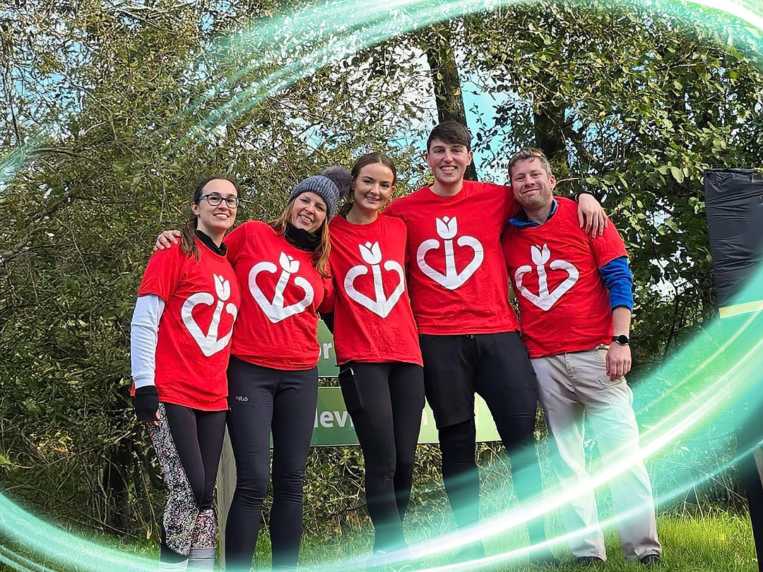 There is a group of 6 people in red shirts and a healthcare logo on them. There is a electric teal and light green neon oval over the photo.