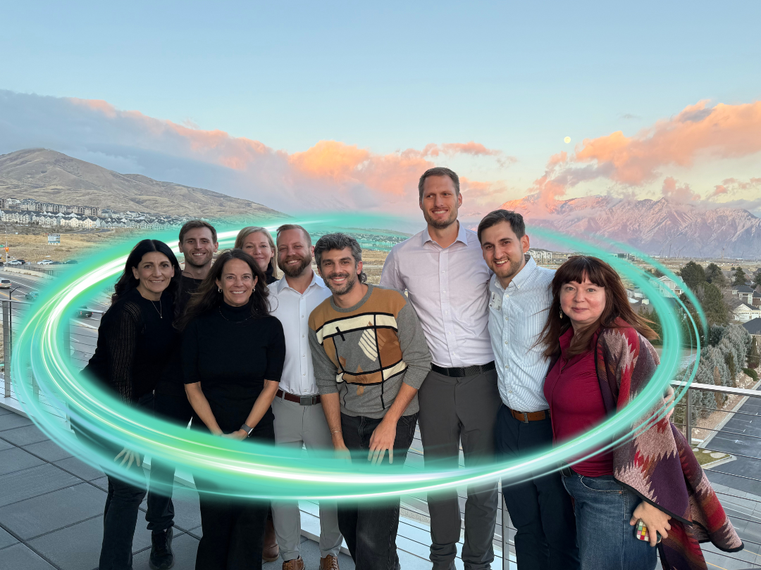 A group of people in Salt Lake City area outside with a sunset smiling and an electric teal swirl circling them.