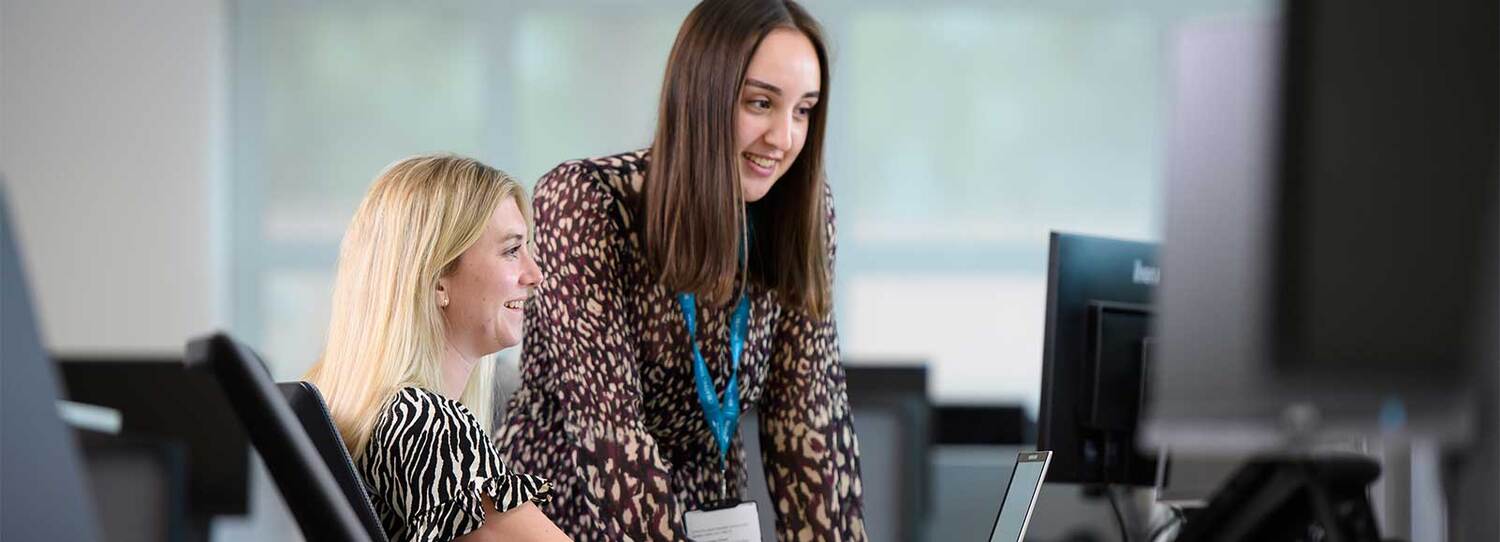 Two women looking at the screen in an office