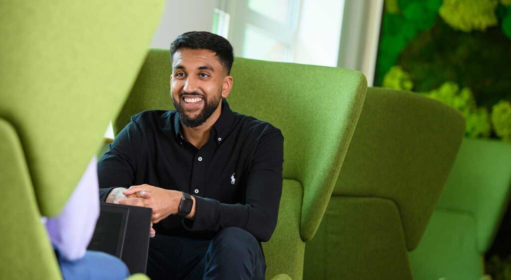 man smiling while sitting on a green armchair in the Leatherhead office